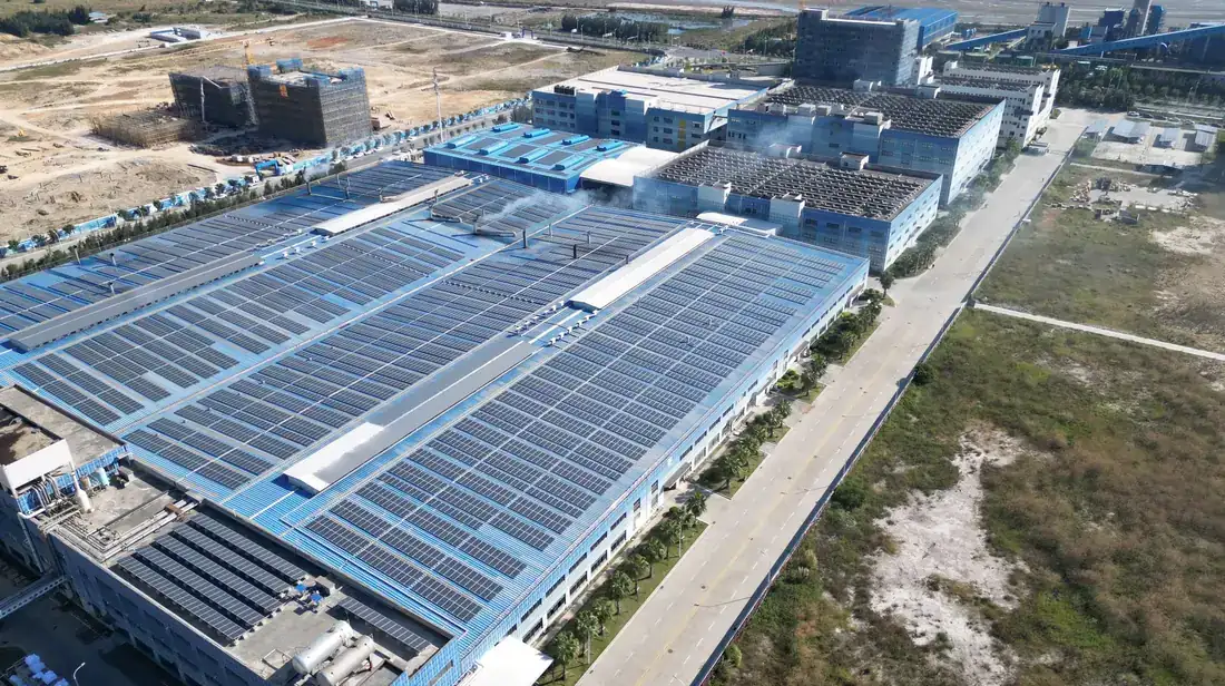 Aerial view of solar modules covering the roofs of a large industrial complex.